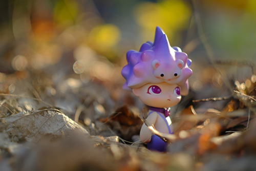 ツバキアキラが撮った、POPMART・DIMOO・はぐれ動物シリーズ。枯れ葉の中に浮かび上がるような、紫色のハリネズミくん。