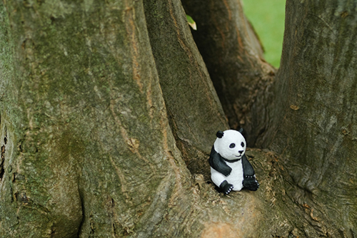 ツバキアキラが撮った、パンダのフィギュア。大きな木のもとに、ポツンと座っているパンダ。